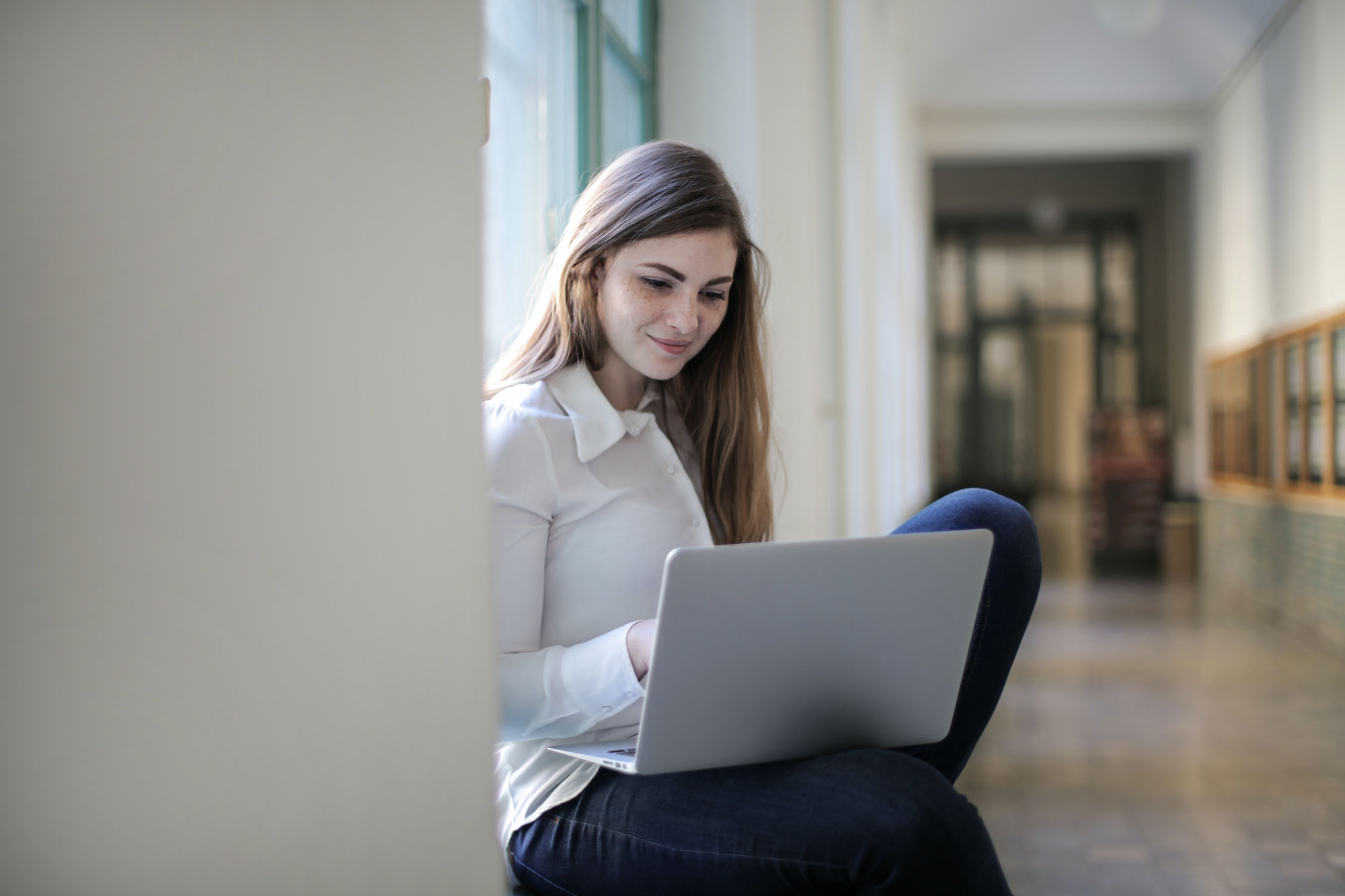 Teenage girl using a laptop in a hallway